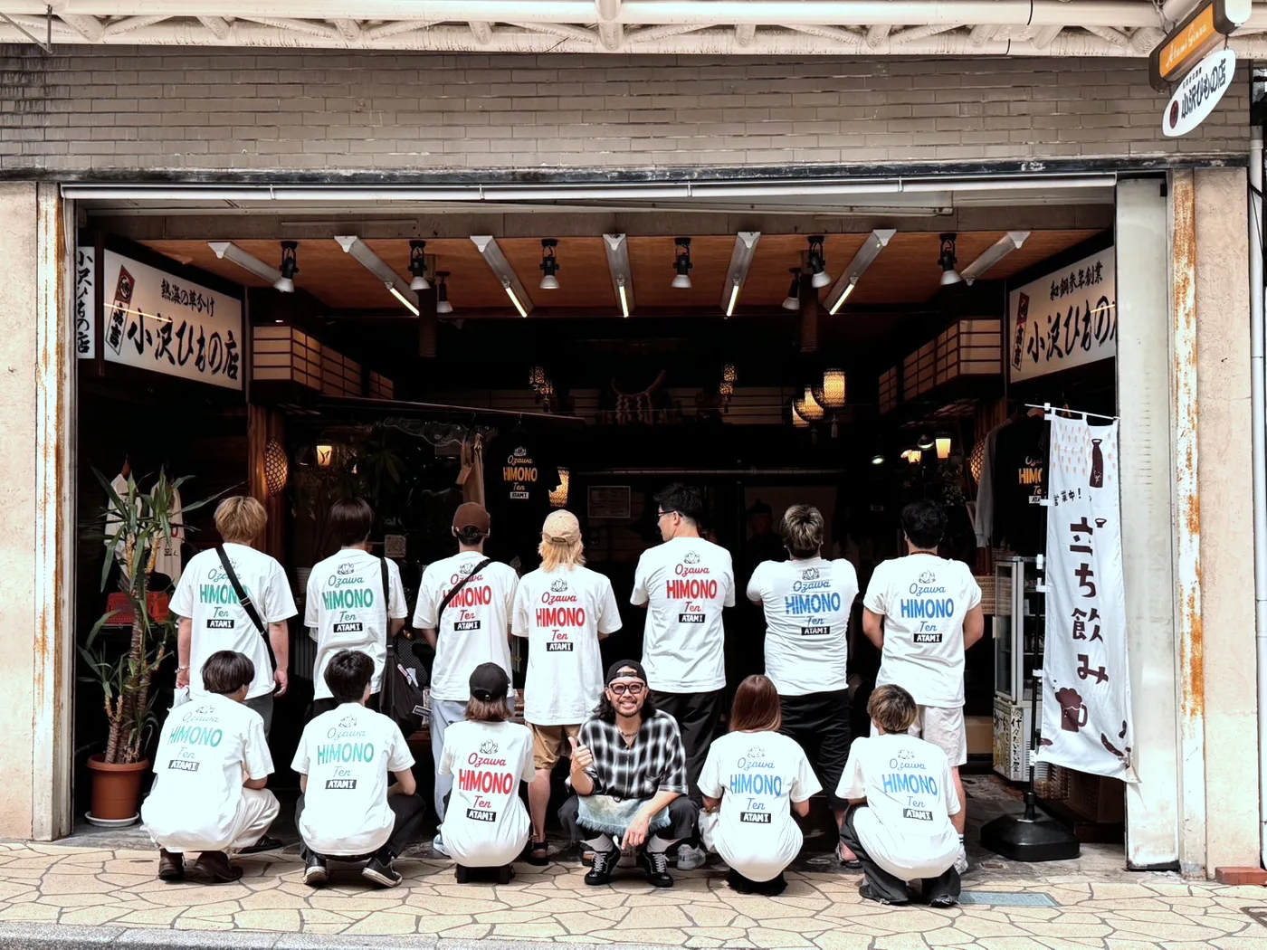 店名のロゴを背中に入れたおそろいの白いTシャツを着て、店先に並ぶ小沢ひもの店のスタッフ