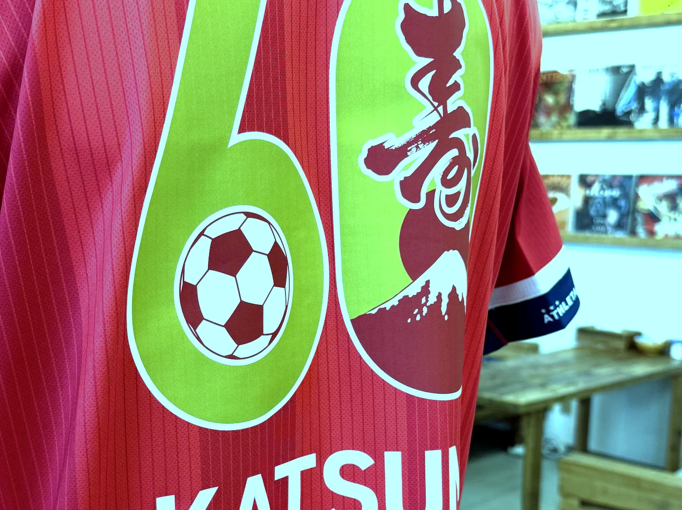 赤いサッカーユニフォームの背中に入った黄緑色の背番号6と、富士山とサッカーボールをあしらったデザイン