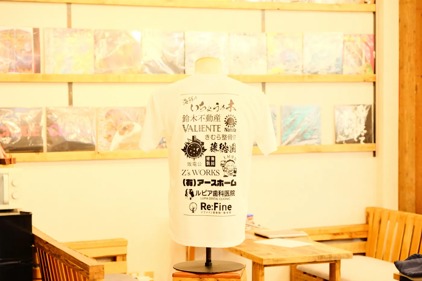 背中いっぱいにスポンサー各社のロゴを並べてプリントした白いTシャツの後ろ姿