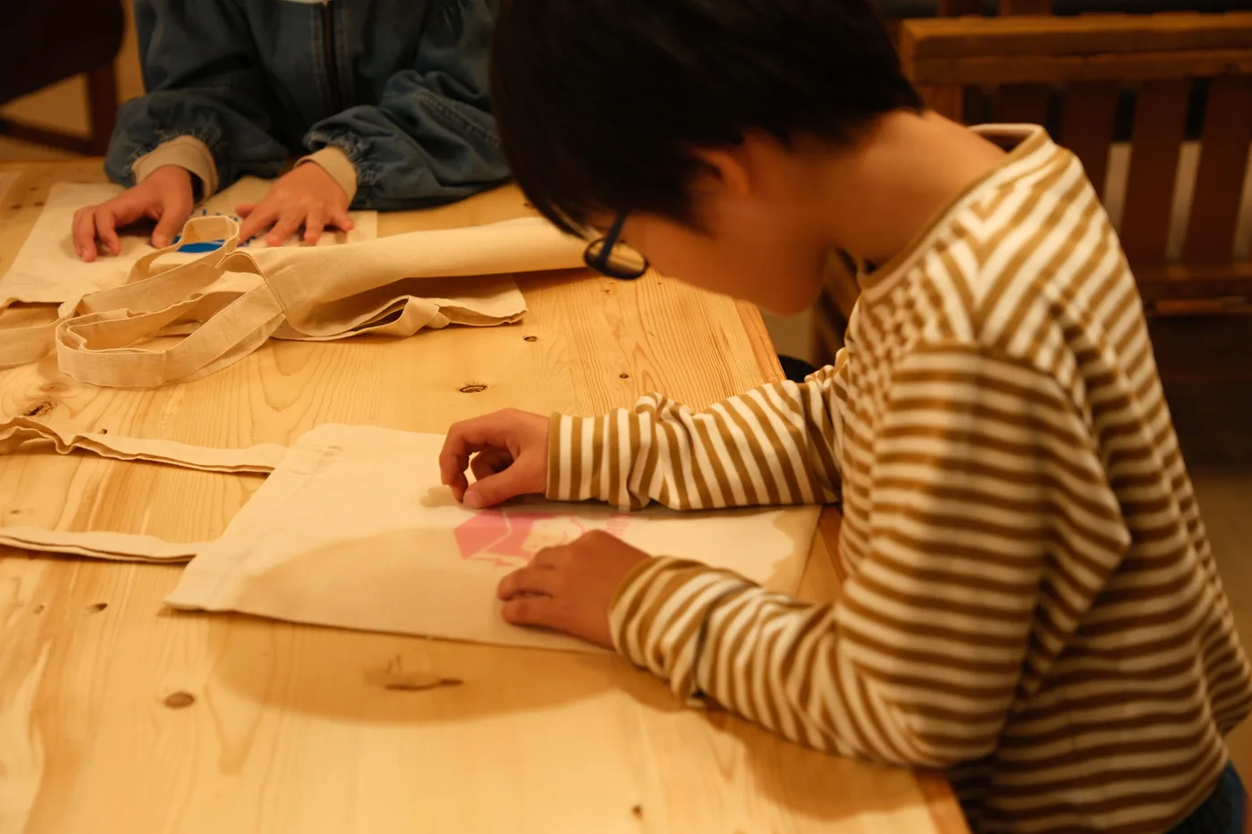 作業台でトートバッグのデザインを描く手もと